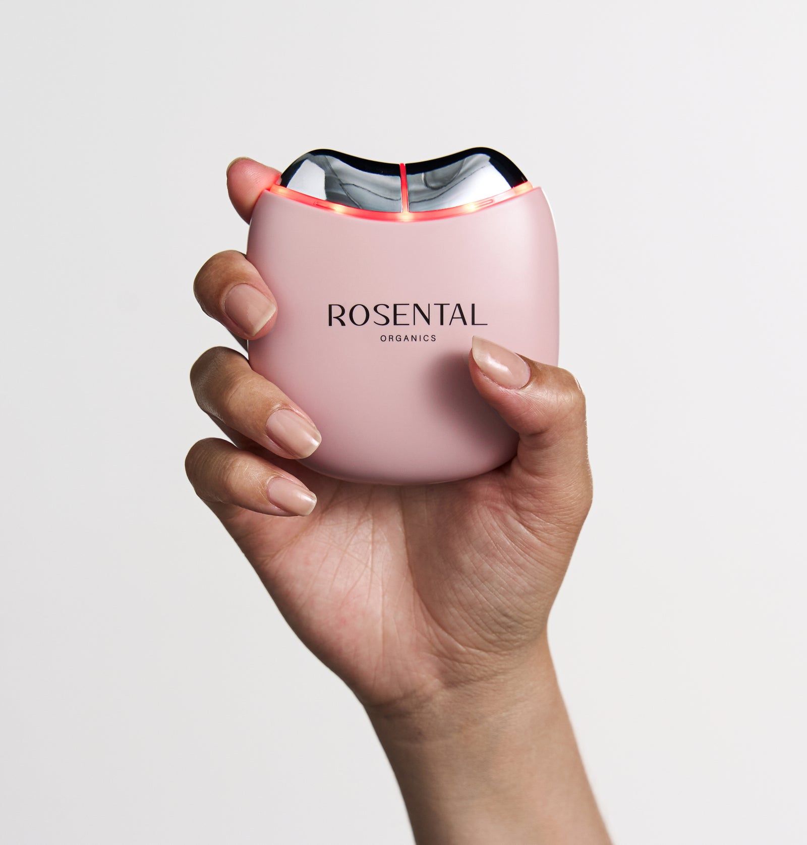 Rosa Gerät mit der Aufschrift "ROSENTAL ORGANICS". Das Gerät wird von einer Hand gehalten. Rote Lichter sind sichtbar.
