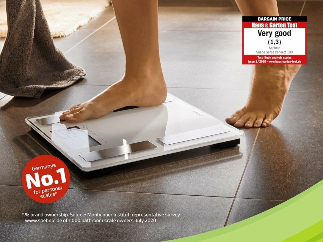 Bilancia in uso. Piedi sulla bilancia. Asciugamano sullo sfondo. Valutazione 'Very good'.