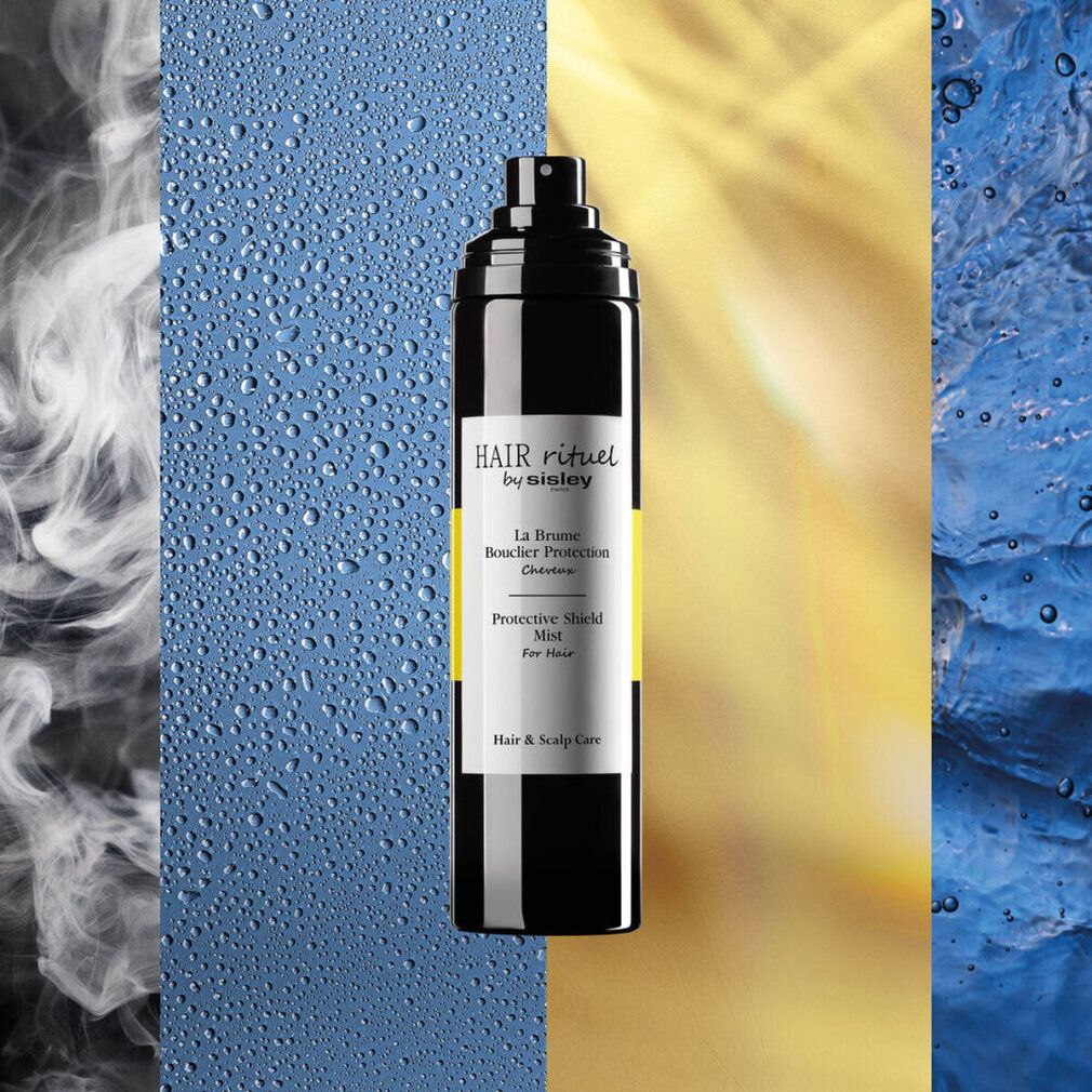 Schwarze Sprühflasche mit gelbem Streifen. Aufschrift: HAIR rituel by sisley, La Brume Bouclier Protection, Protective Shield Mist. Hintergrund.