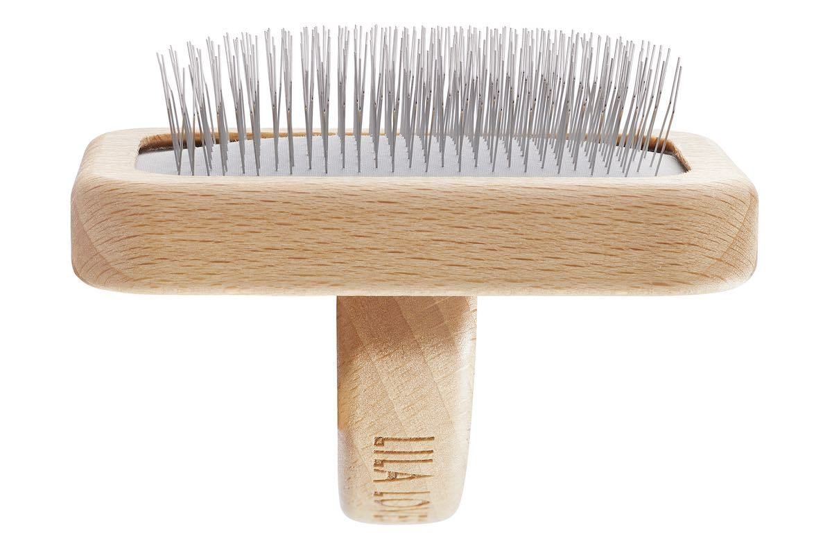 Rechteckige Bürste aus Holz mit Metallborsten und kurzem Griff. Aufschrift: LILA LOVES IT.
