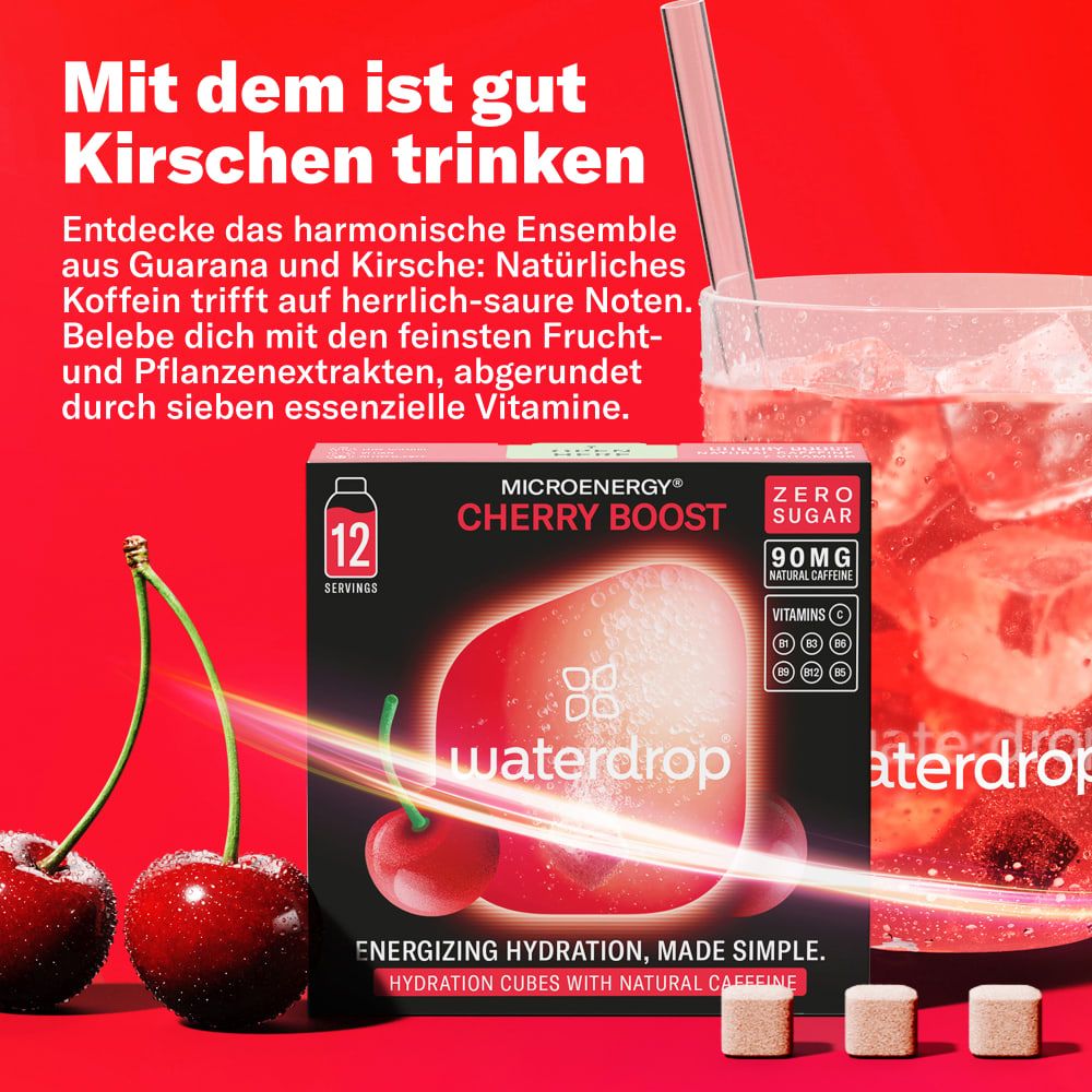 Glas mit Getränk, Kirschen, Eiswürfeln und Produktverpackung. Aufschrift: Microenergy Cherry Boost, 12 Portionen, ohne Zucker, 90mg, Vitamine.