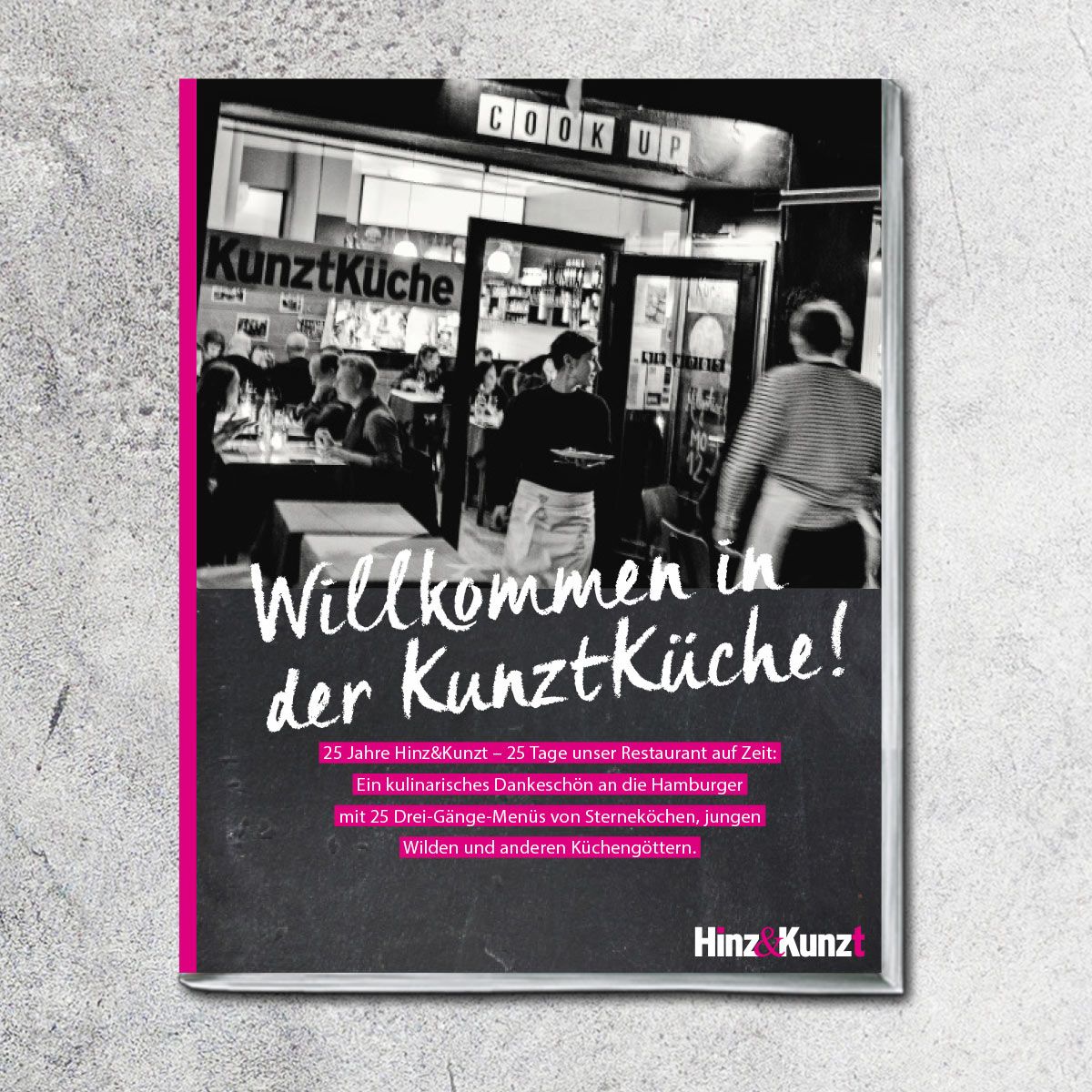 Buchcover mit dem Titel „Willkommen in der KunztKüche!“. Schwarzer Hintergrund mit weißer Schrift. Rosa Rahmen. Restaurant-Szene im Hintergrund.