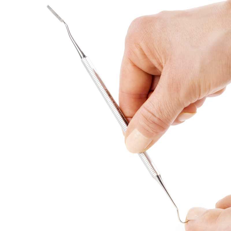 Hand benutzt ein Nagelpflegeinstrument mit Haken und Feile.
