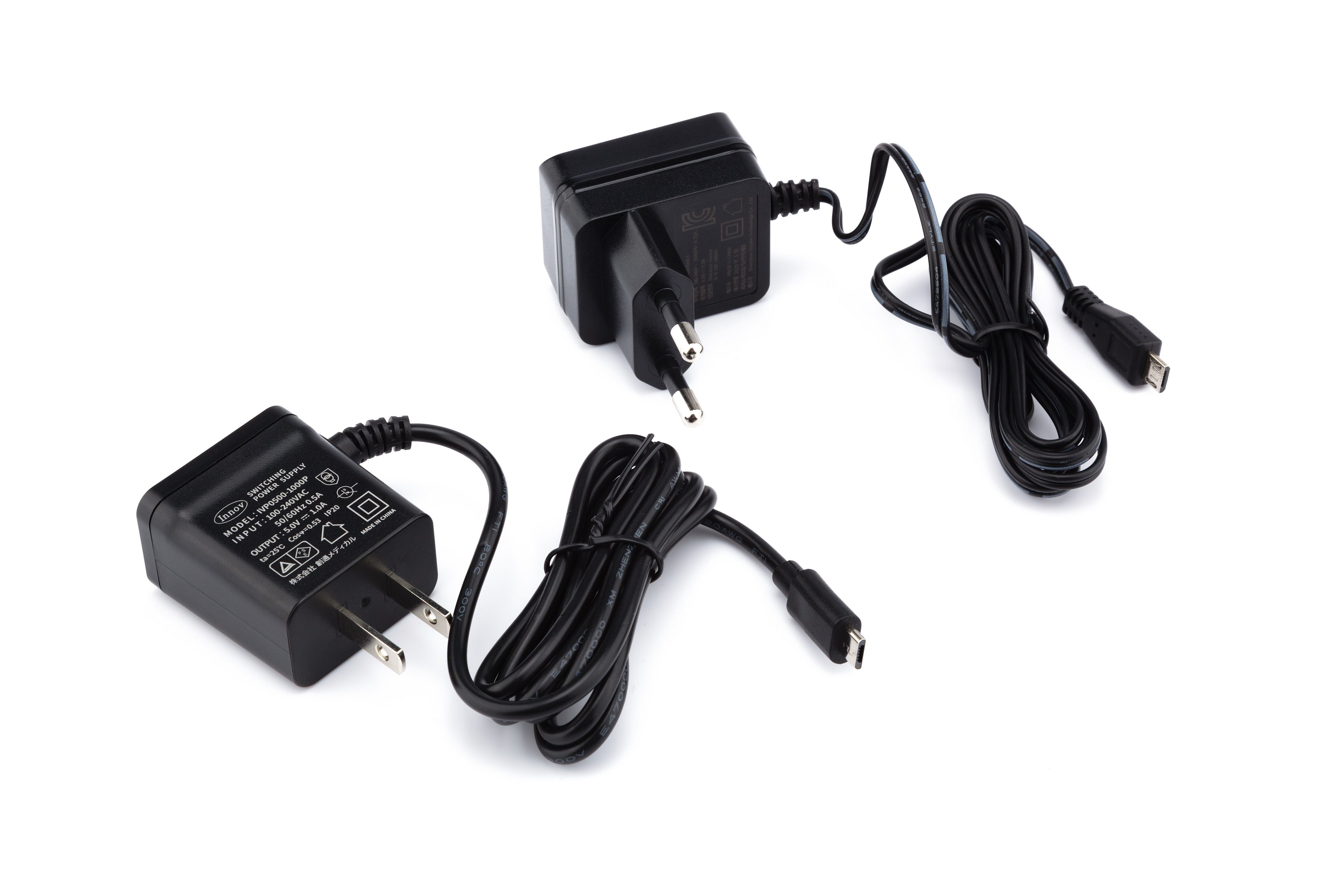 Zwei schwarze Netzteile mit Kabeln. Unterschiedliche Stecker. Auf weißem Hintergrund.