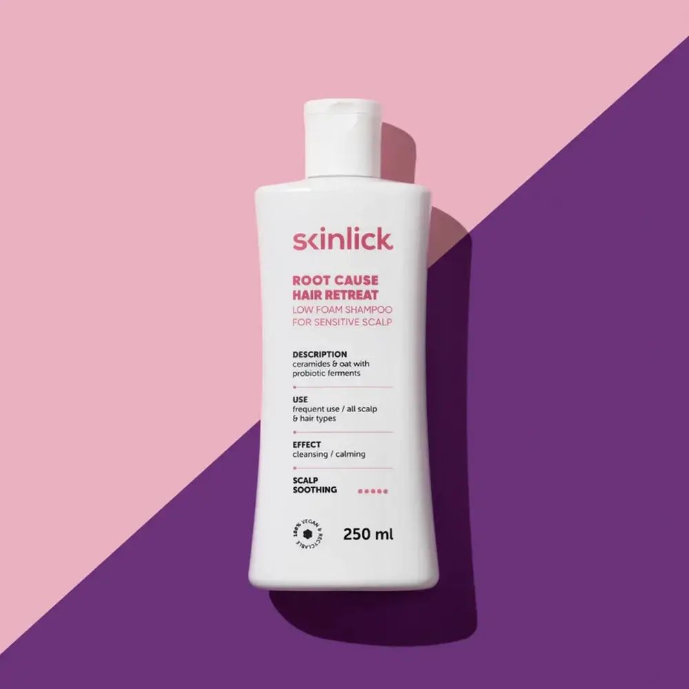 Weißes Shampoo-Fläschchen mit rosa Schriftzug. SKINLICK Root Cause Hair Retreat. 250 ml. Auf rosa-lila Hintergrund.