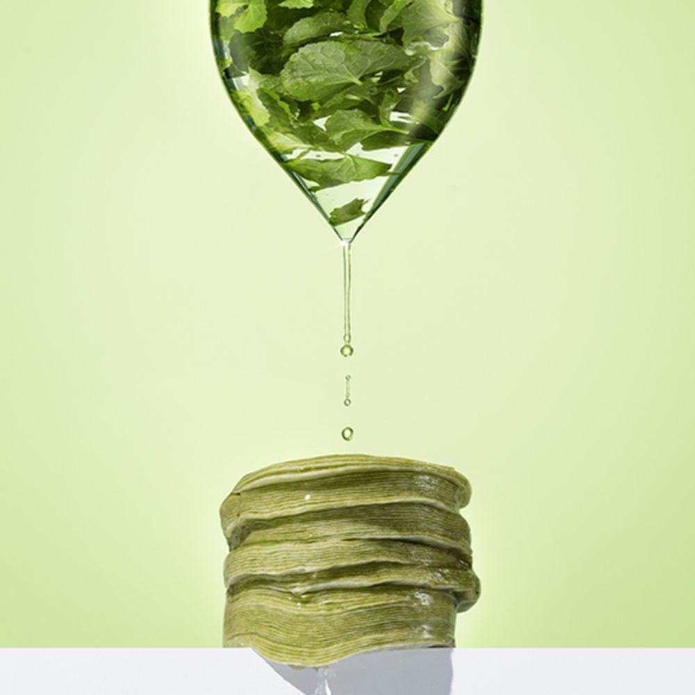 Grüne Pads werden von einer Flüssigkeit aus einem Behälter gegossen. Der Behälter hat die Form eines Blattes.