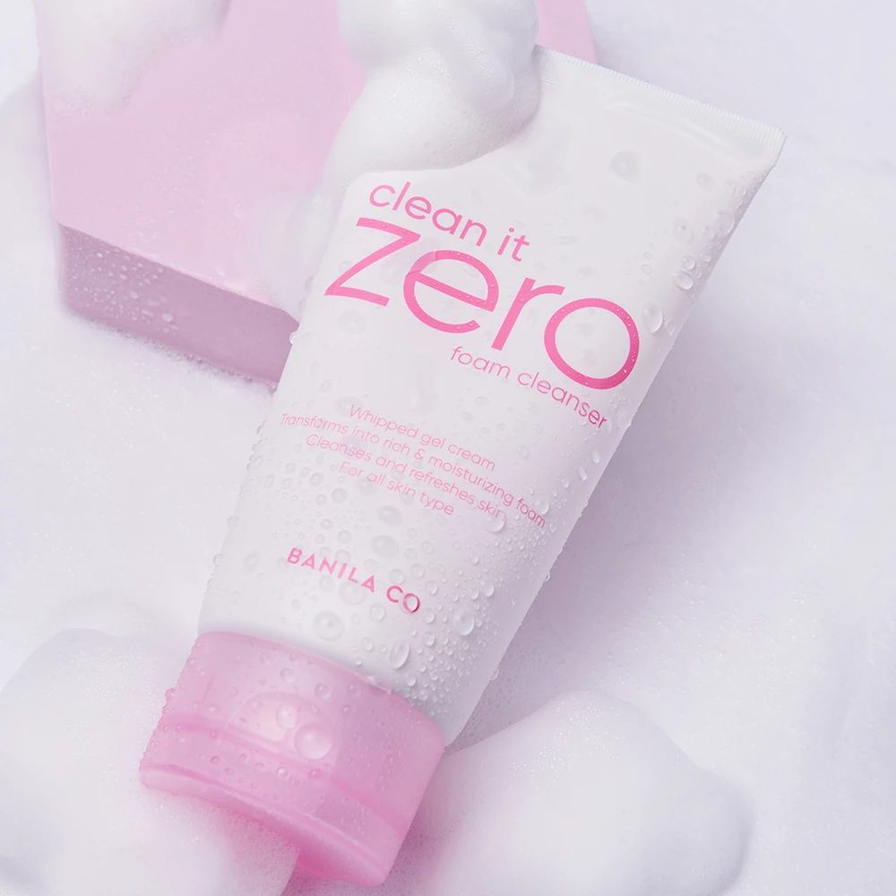 Weiße Tube mit rosa Deckel, umgeben von Schaum. Aufschrift "clean it zero foam cleanser" und "BANILA CO".
