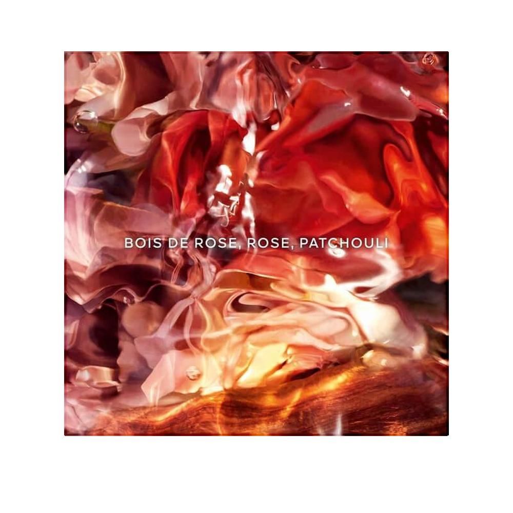 Quadratische Verpackung mit floralem Design. Text: Bois de Rose, Rose, Patchouli. Farbverlauf von Rot- und Orangetönen.