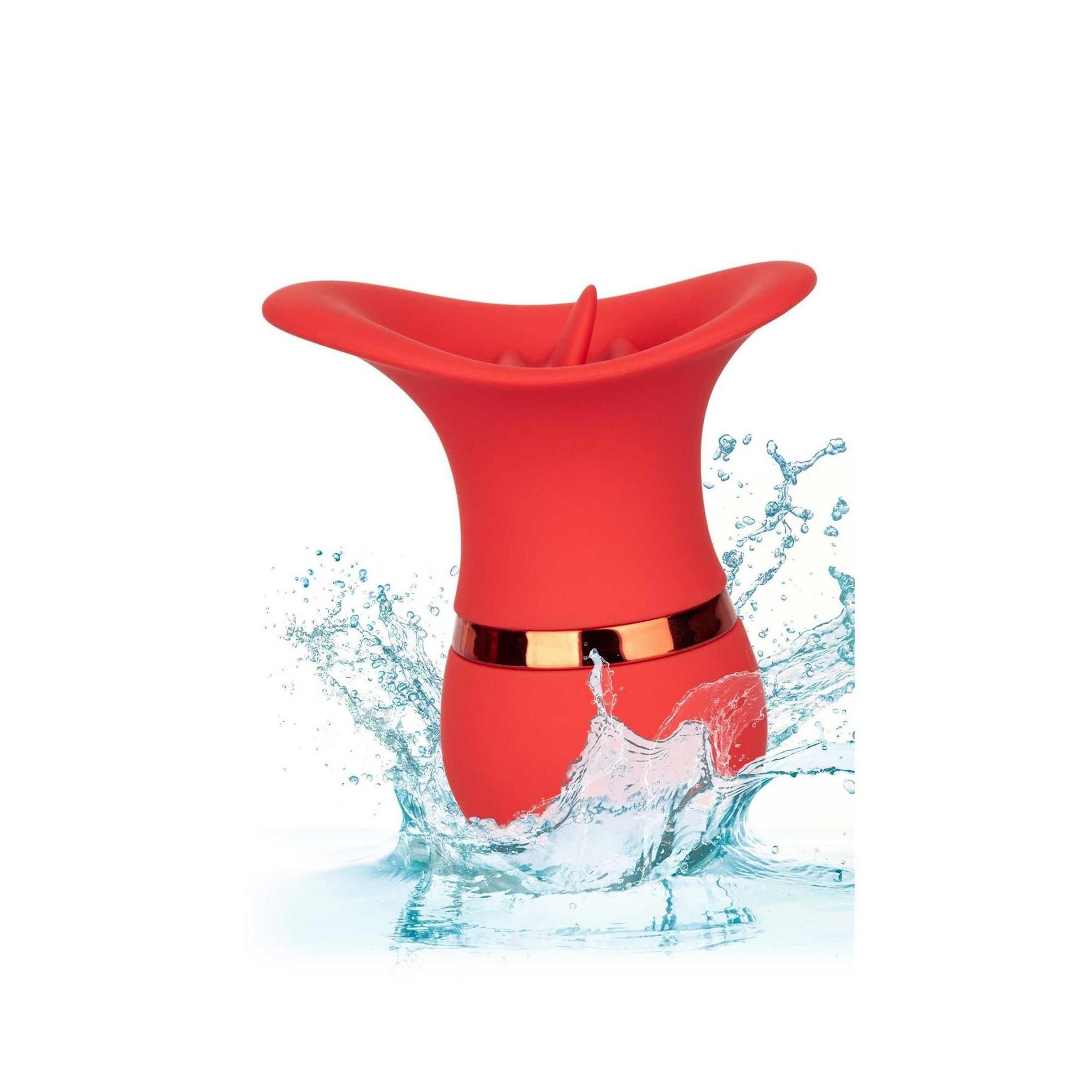 Roter Charmer mit Wasserspritzern. Goldfarbener Ring. Oberteil mit geriffelter Öffnung. Wasser spritzt um das Produkt.