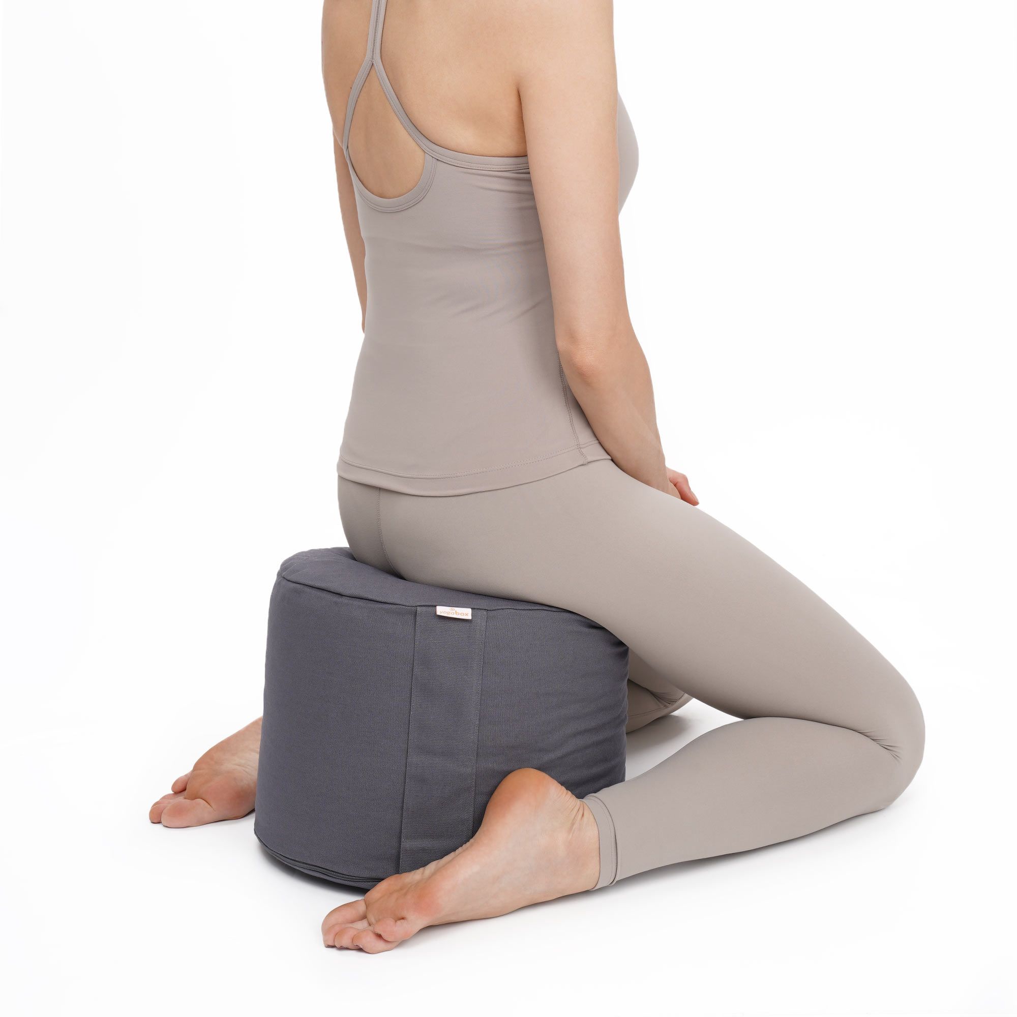 Frau sitzt auf grauem Meditationskissen Rondo Big BASIC in Meditationshaltung.