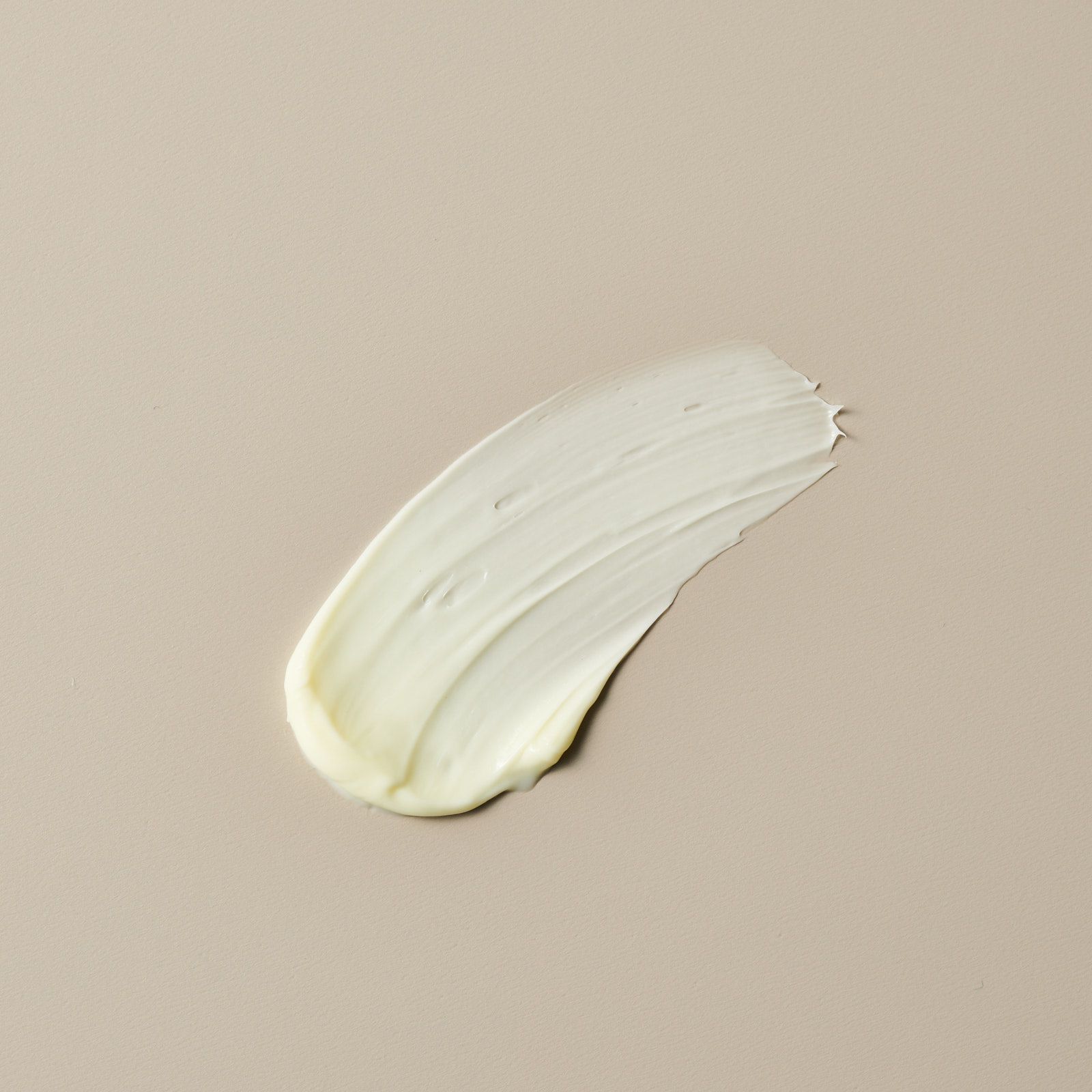 Creme-Abstrich auf beigem Untergrund. Die Textur ist cremig und weiß.