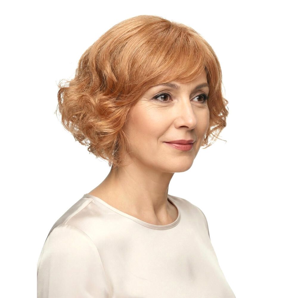 Frau mit rotblonder Perücke. Welliges Haar, Pony. Dreiviertelansicht, helles Oberteil.