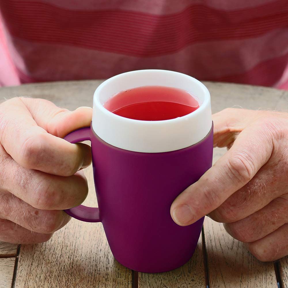 Lila Becher mit weißem Rand, gefüllt mit roter Flüssigkeit. Hände halten den Becher.