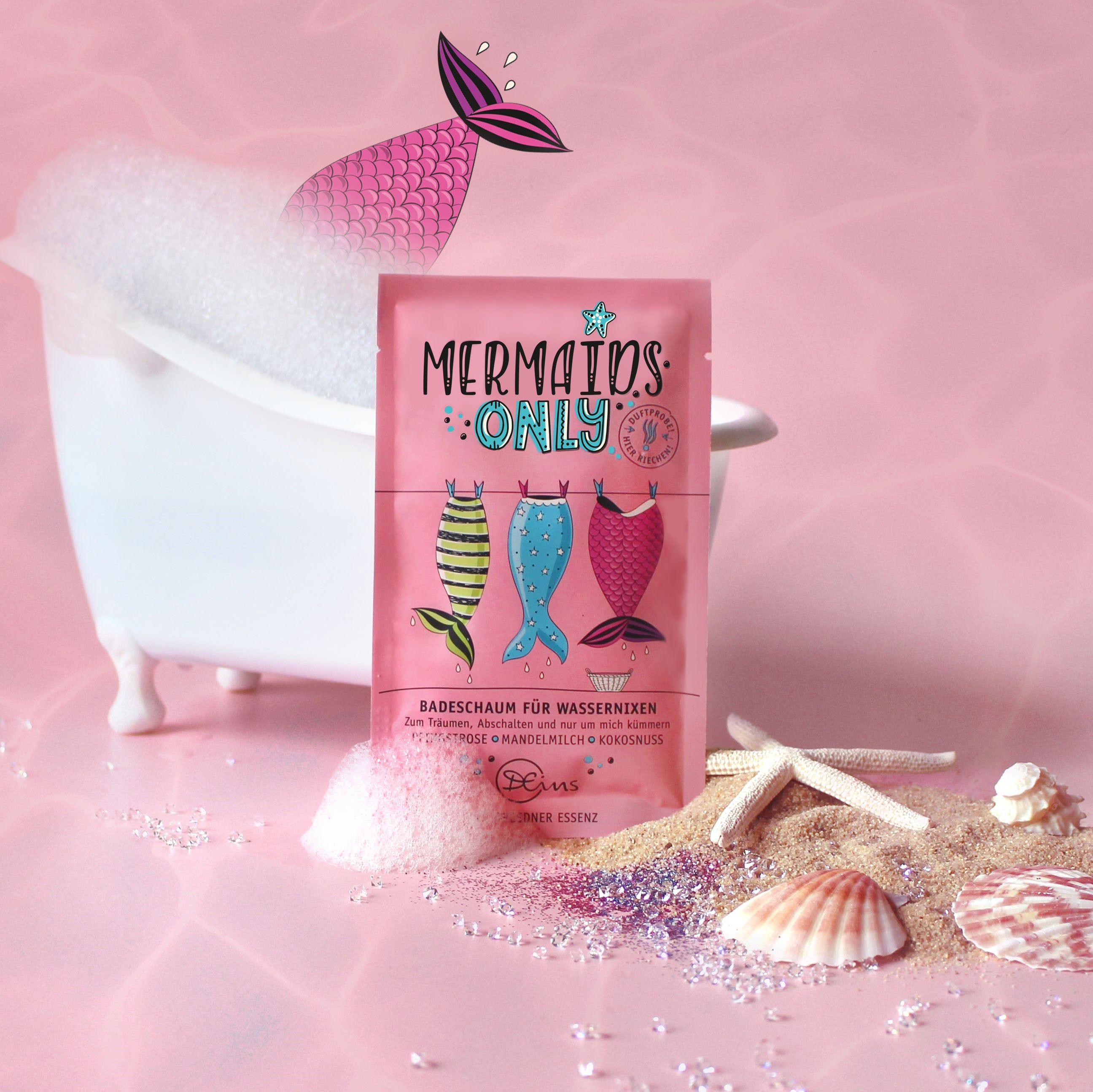 Roze verpakking met "Mermaids Only" en zeemeerminstaarten. Product in badkuip met schuim, schelpen en zand. Merk: Dresdner Essenz.