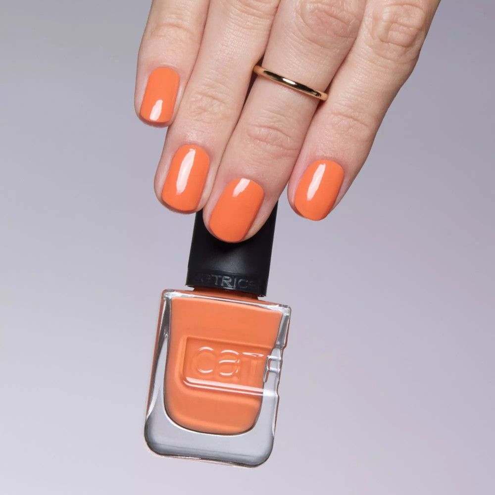 Hand mit lackierten Nägeln in Orange. Nagellackflasche mit schwarzem Deckel. Catrice-Logo sichtbar.