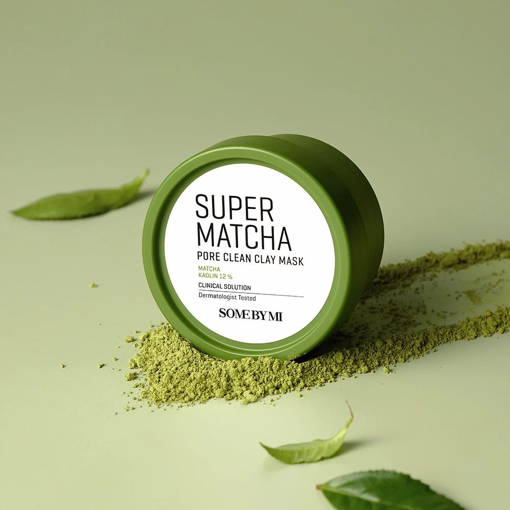 Grüner Behälter mit weißem Deckel. Aufschrift: Super Matcha Pore Clean Clay Mask. Grüntee-Blätter.