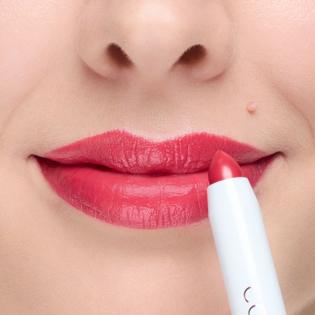 Roter Lippenstift wird auf Lippen aufgetragen. Der Lippenstift ist in einem weißen Stiftgehäuse.