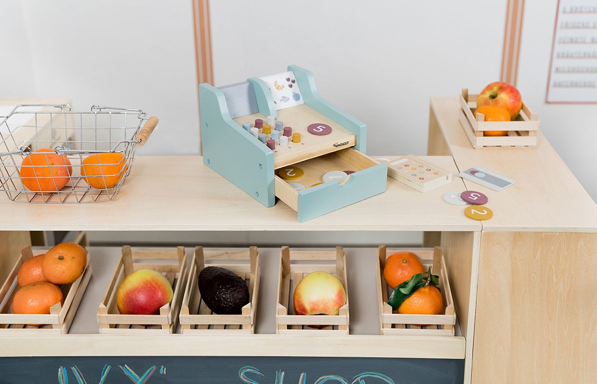 Spielkasse mit Obst und Gemüse in einem Spielzeugladen. Kasse mit Knöpfen und Schublade. Zubehör.