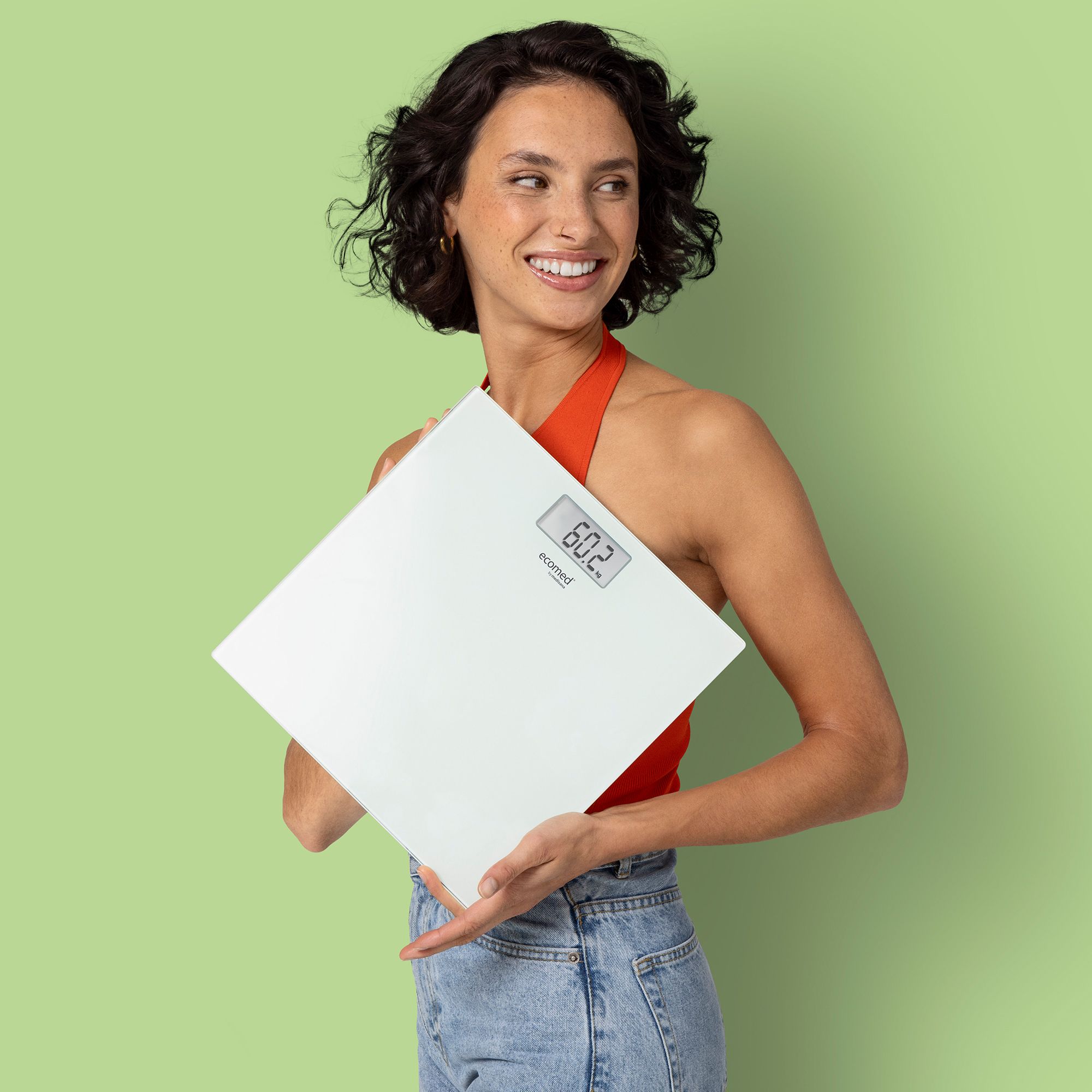 Frau hält eine weiße Glas Personenwaage mit digitaler Anzeige (60.2 kg).