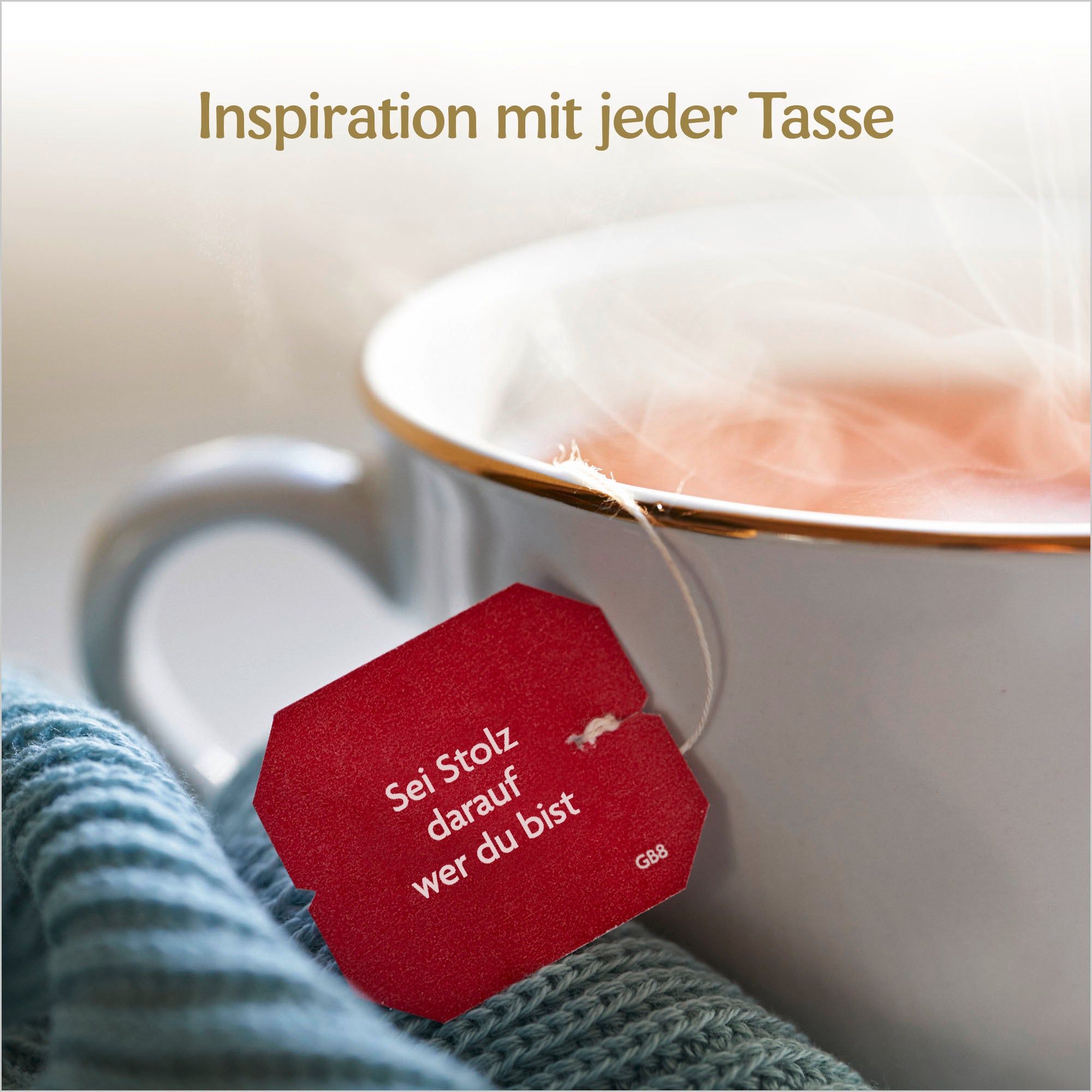Tasse Tee mit rotem Teebeutel. Text auf Teebeutel: Sei Stolz darauf wer du bist. Text: Inspiration mit jeder Tasse.
