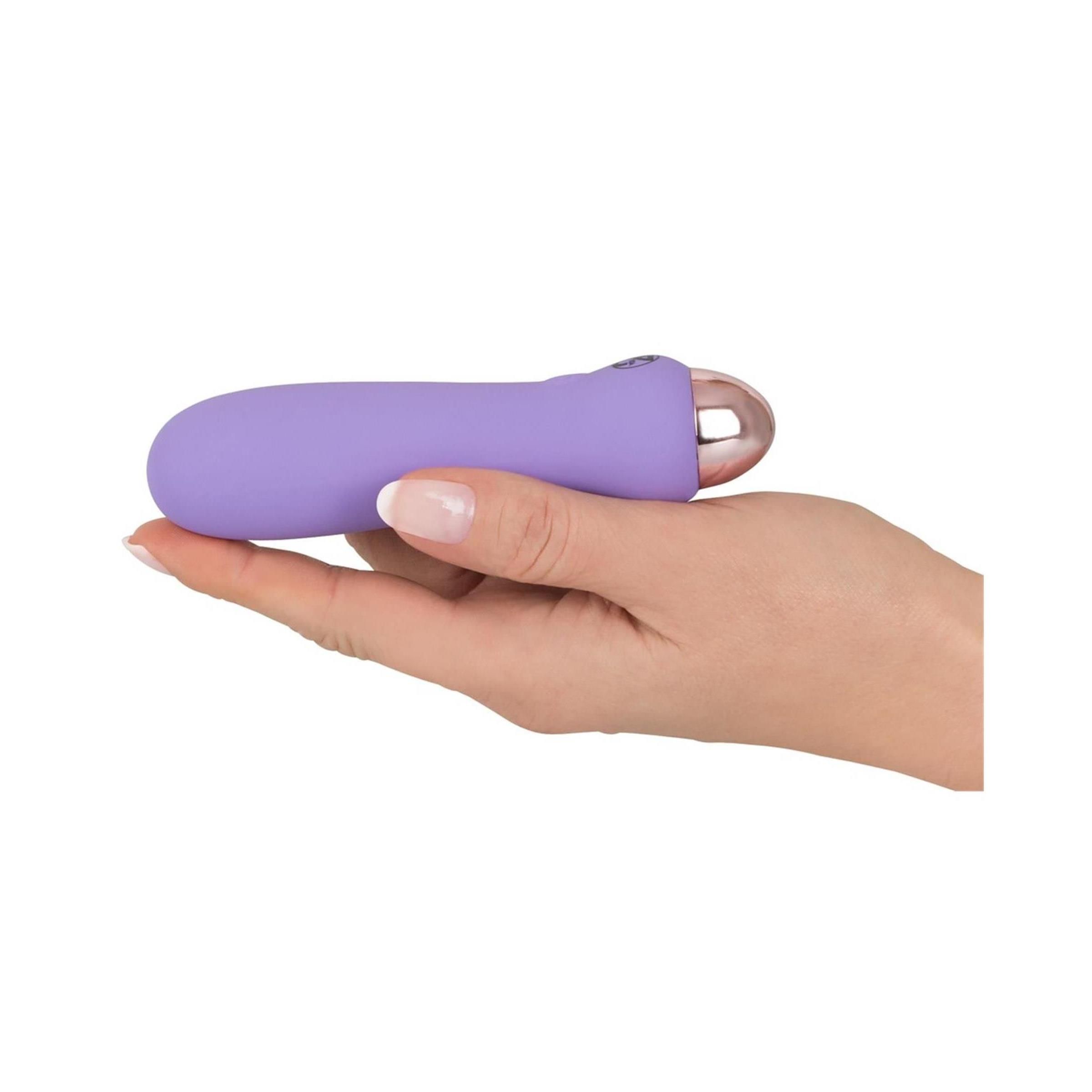 Lila Vibrator in einer Hand gehalten. Rosafarbener Kopf. Glatte Oberfläche.