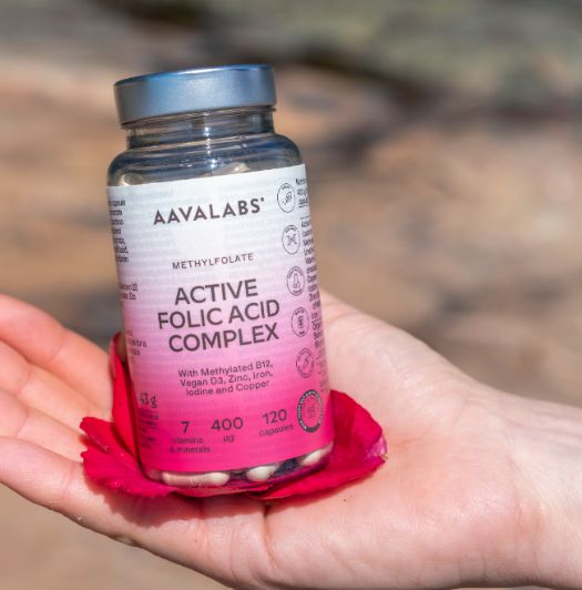 Aavalabs Folsäure Komplex Flasche in einer Hand auf roter Blüte.