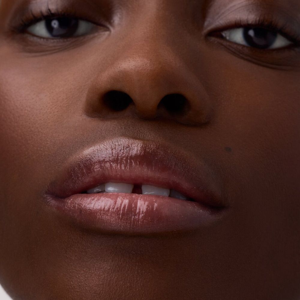 Nahaufnahme von Lippen mit glänzendem Lippenbalsam. Rosa Farbton, glänzendes Finish.