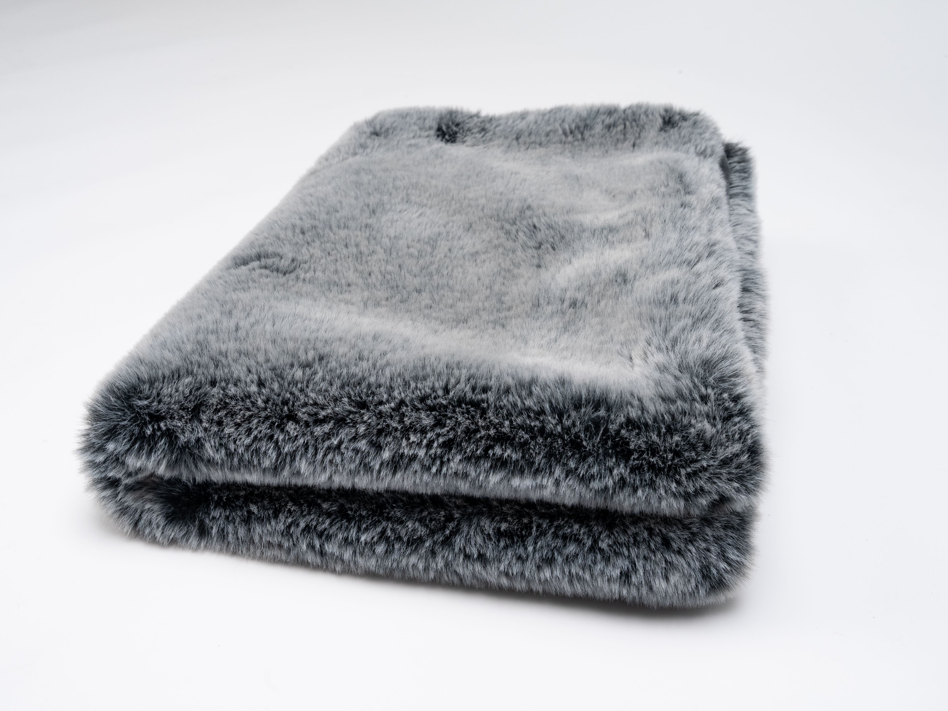 Gefaltete graue Hundedecke. Weiches, flauschiges Material. Auf weißem Hintergrund.