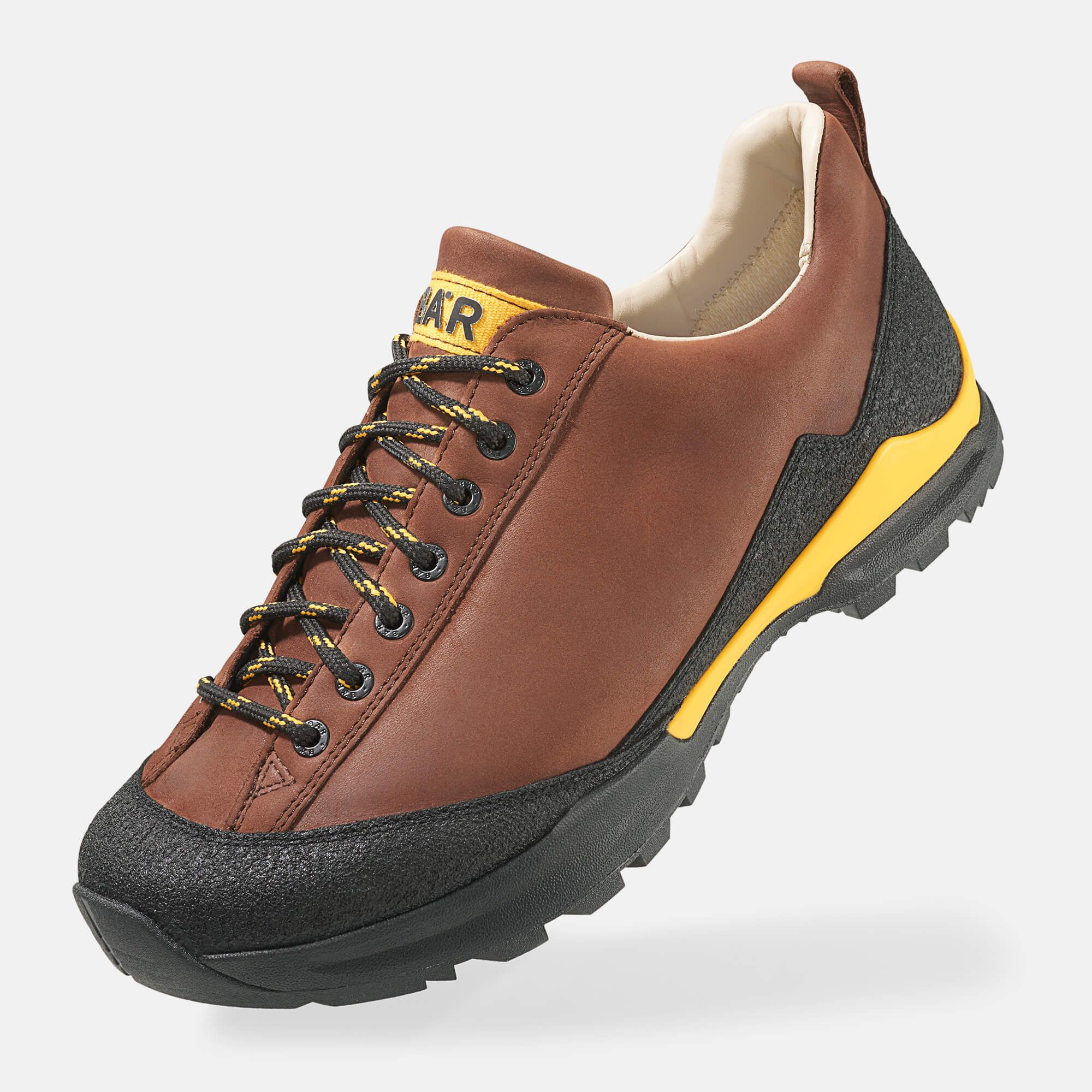 Brauner Wanderschuh mit schwarzer Sohle und Schnürsenkeln. Gelbe Akzente und das Wort "BÄR" sind sichtbar.