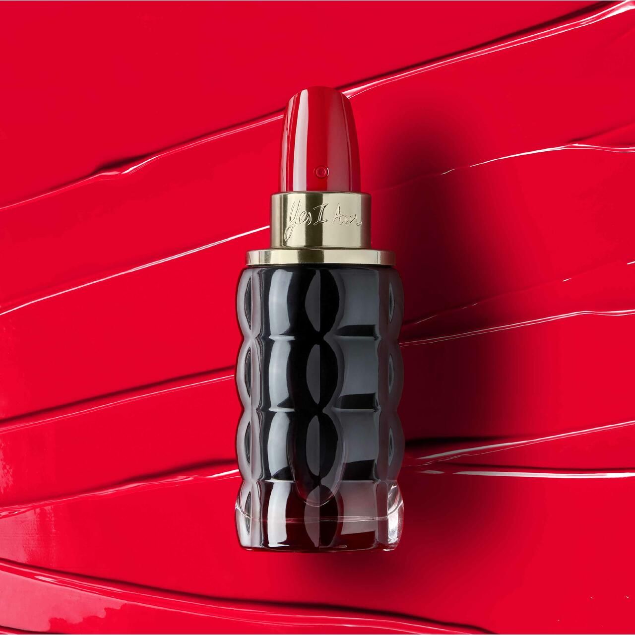 Parfümflasche, schwarz-violett, lippenstiftförmiger Verschluss. Auf rotem Hintergrund.