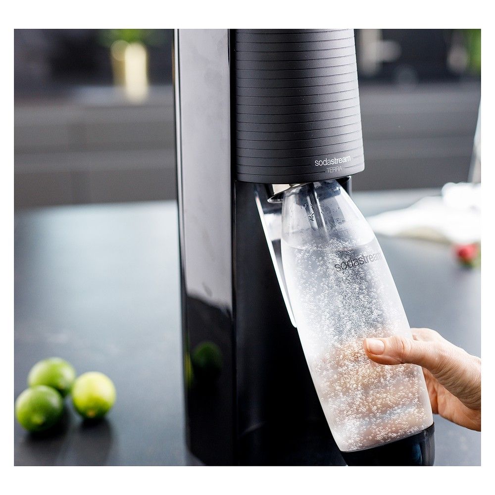 Hand setzt eine gefüllte Kohlensäureflasche in den SodaStream Terra ein.
