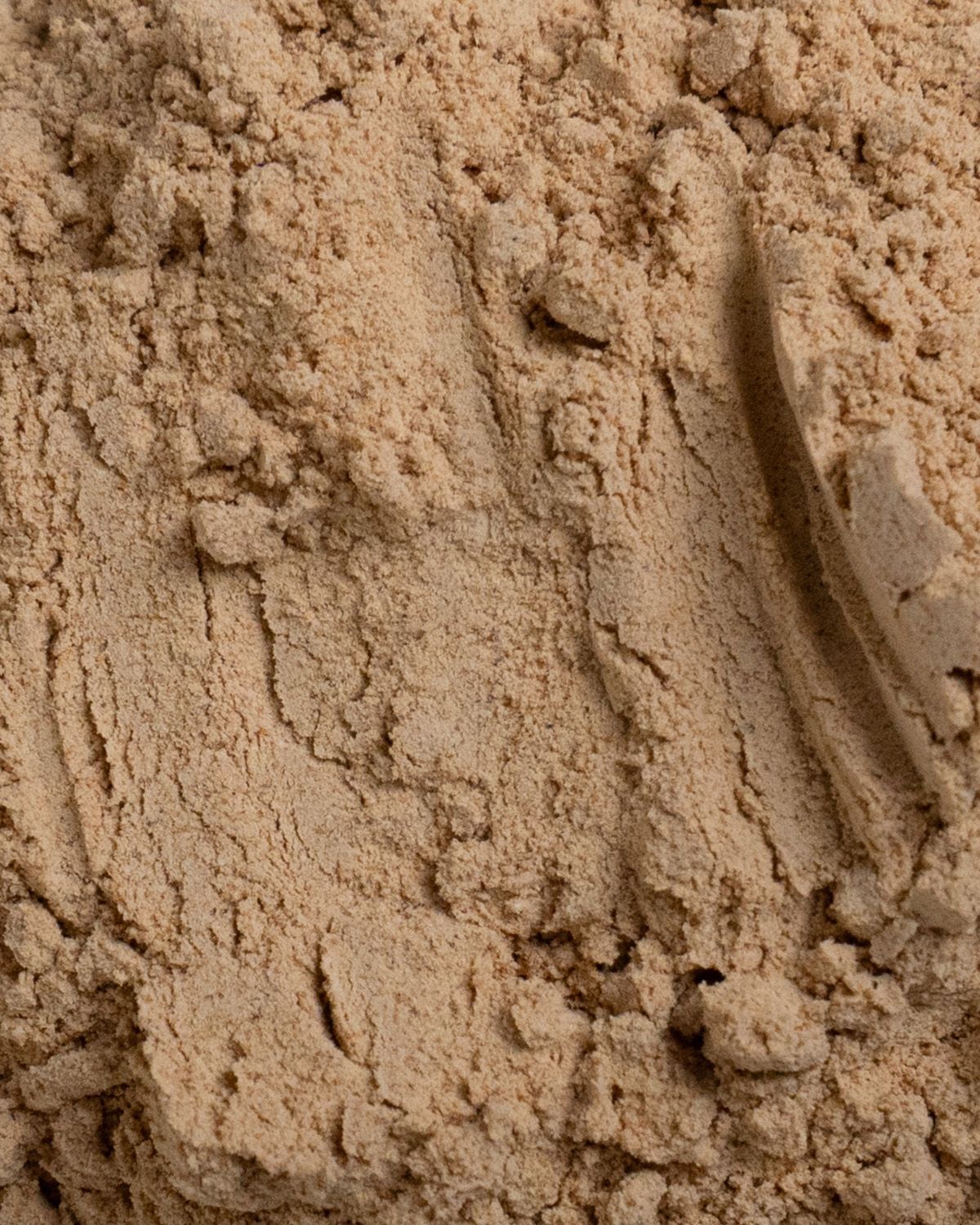 Nahaufnahme von Maca-Pulver. Helle, feine Textur. Oberfläche mit Spuren.