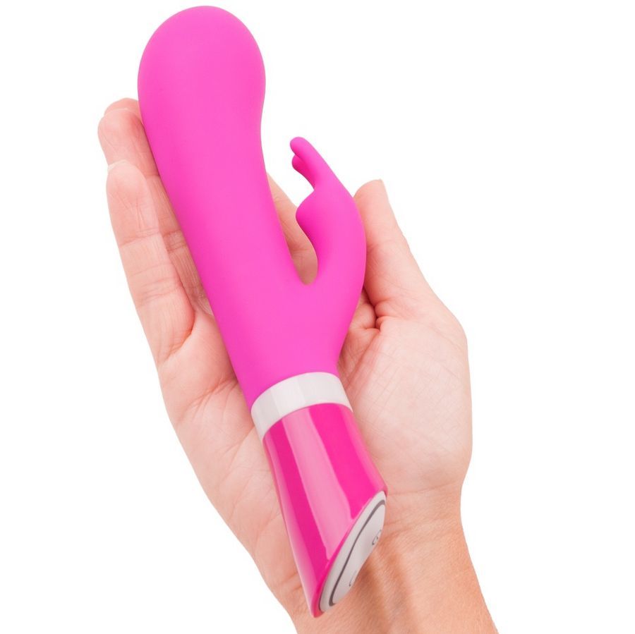 Rosa Vibrator, in einer Hand gehalten. Mit gebogener Form und einem zusätzlichen Element.