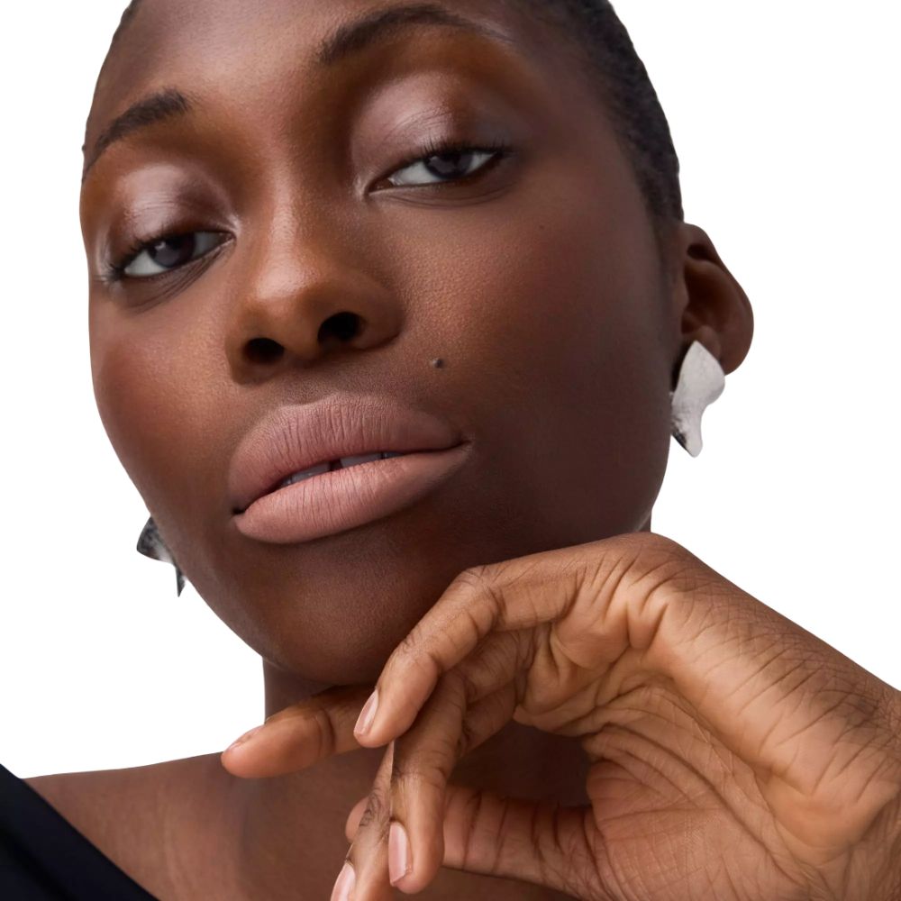 Porträt einer Frau mit hellbraunen Lippen. Sie berührt ihr Kinn.