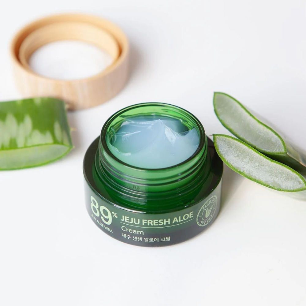 Offenes Cremeglas mit Aloe Vera-Gel. Aloe Vera-Blätter und Deckel daneben. Aufschrift: 89% Jeju Fresh Aloe Cream.