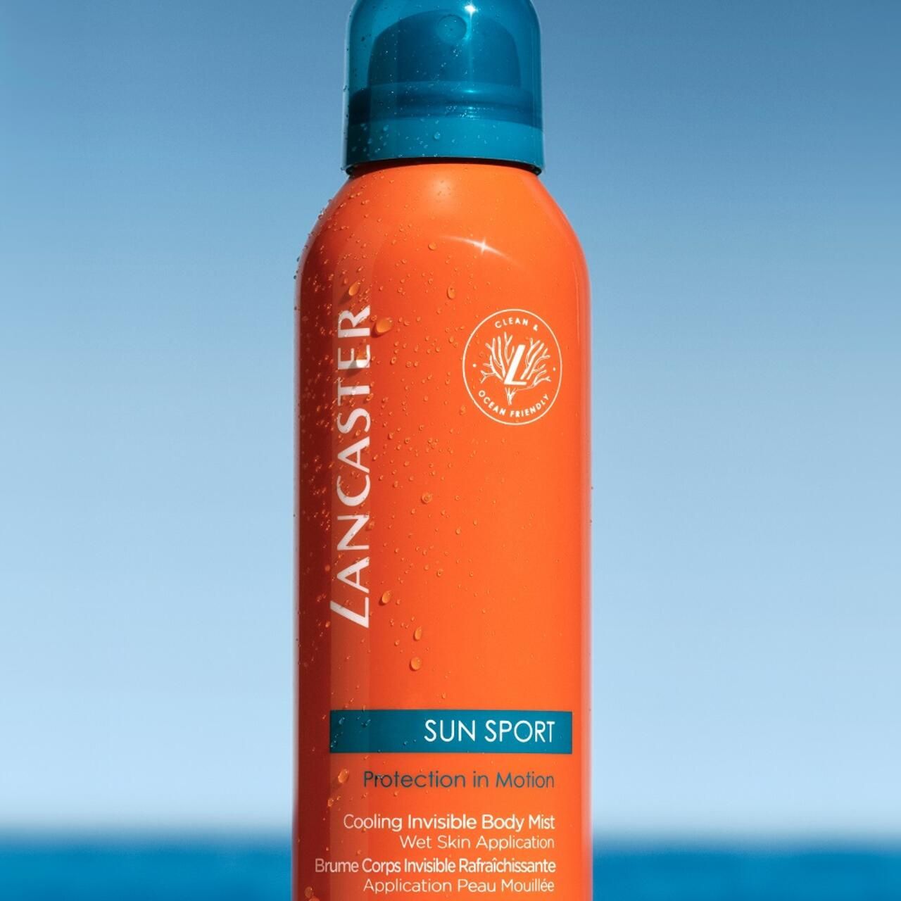 Orangefarbene Sprühflasche mit blauem Deckel. Text: LANCASTER, SUN SPORT. Vegan-Logo. Kühlendes, unsichtbares Körperspray.