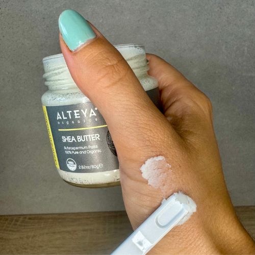 Shea Butter Dose in Hand gehalten. Produkt auf Hand aufgetragen. Etikett mit Markenname und Produktname. 2.82 oz/80g.