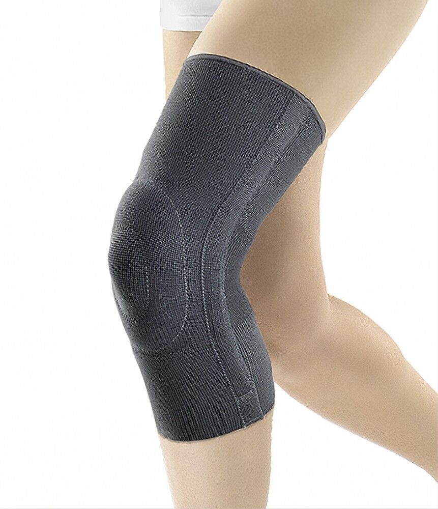 Kniebandage, dunkelgrau, am Bein getragen. Elastisches Material, anatomische Formgebung. Nahtdetails sichtbar.