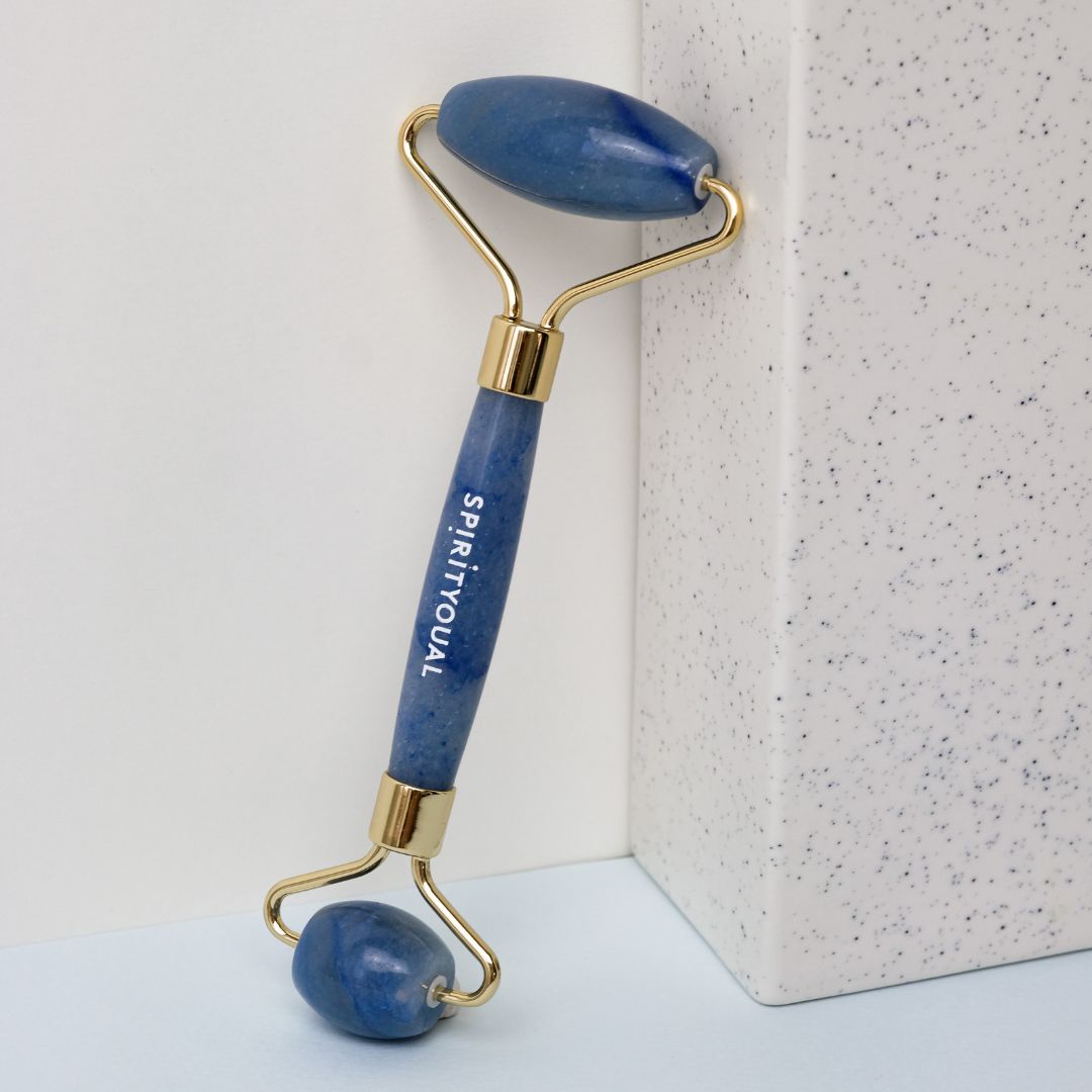 Blauer Aventurin-Beauty-Roller. Goldfarbener Rahmen. Aufschrift SPIRITYOUAL. Auf weißem Hintergrund.