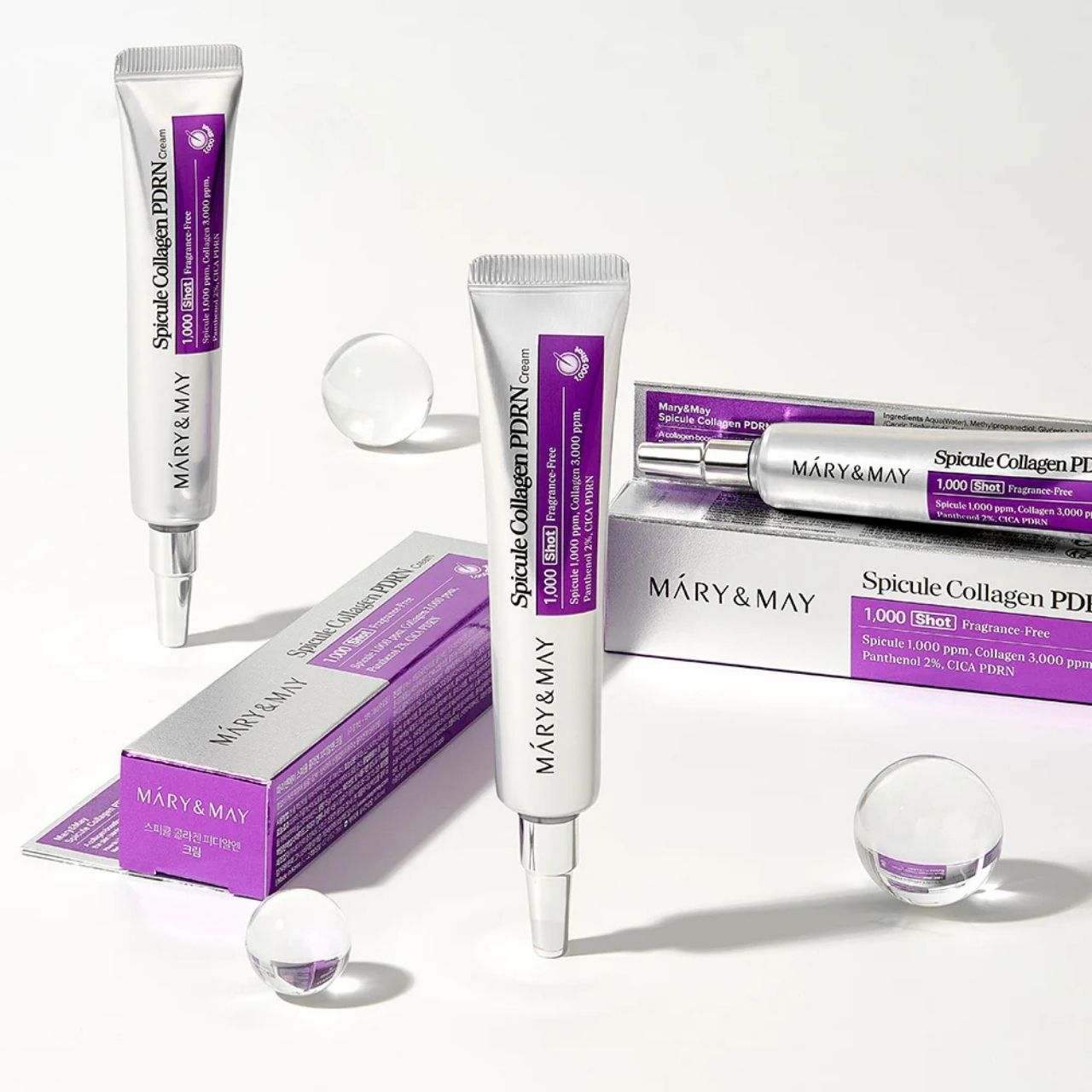 Mehrere Tuben und Kartons von Mary&May Spicule Collagen PDRN Cream mit Glaskugeln.