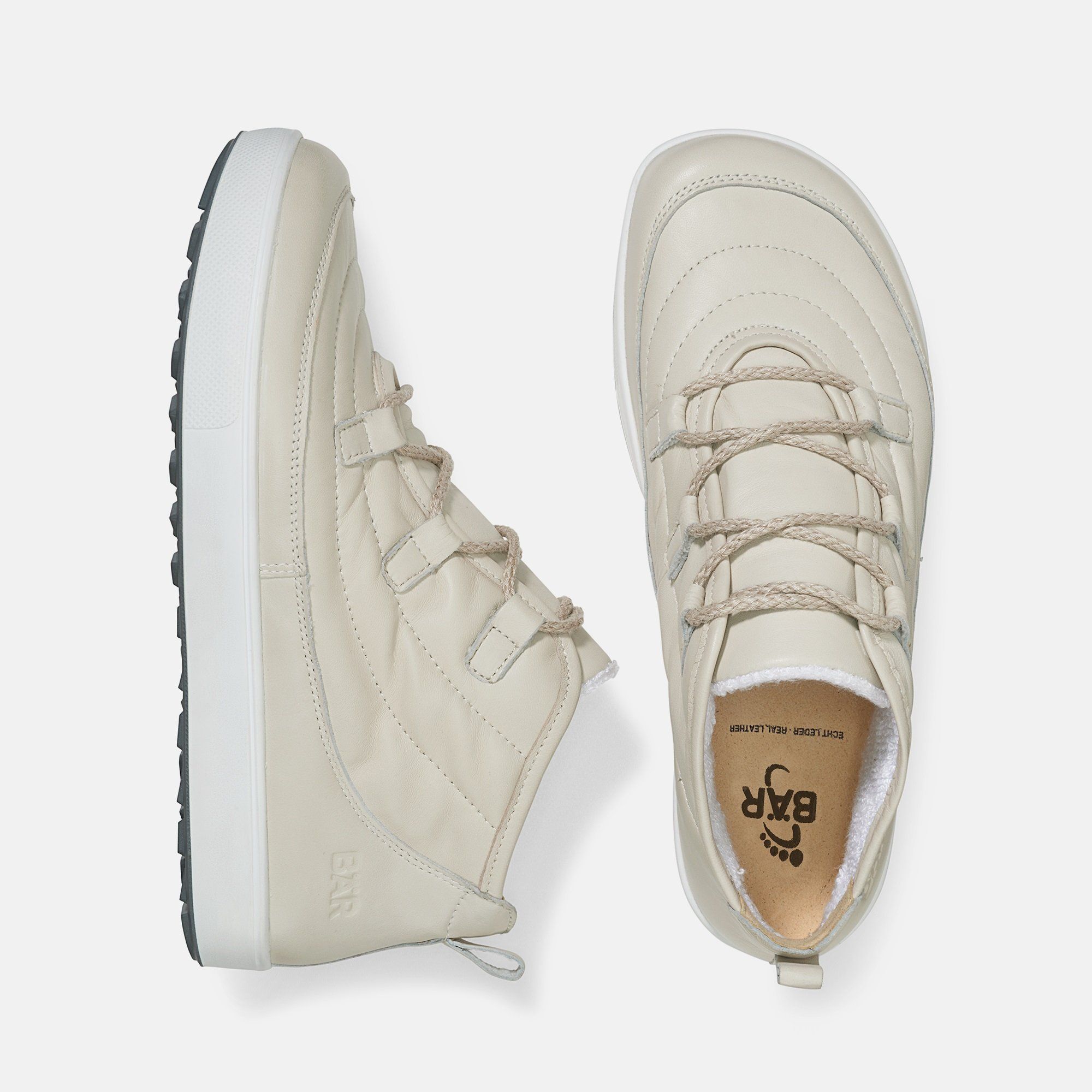 Zwei beige Stiefeletten. Eine von oben, eine von der Seite. Innensohle mit Logo. Weiße Sohle.