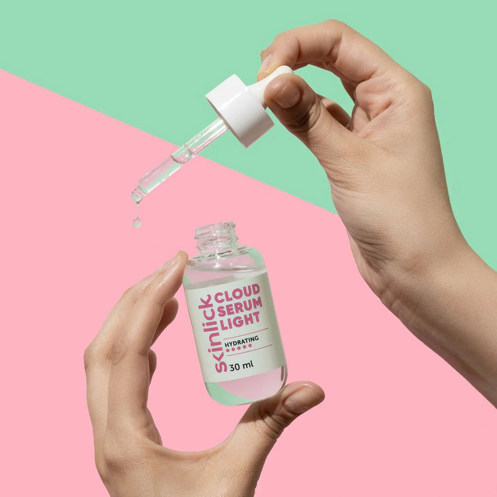 Eine Hand hält eine Glasflasche mit 30 ml "Cloud Serum Light" und einem Pipettenapplikator, aus dem Tropfen fallen.