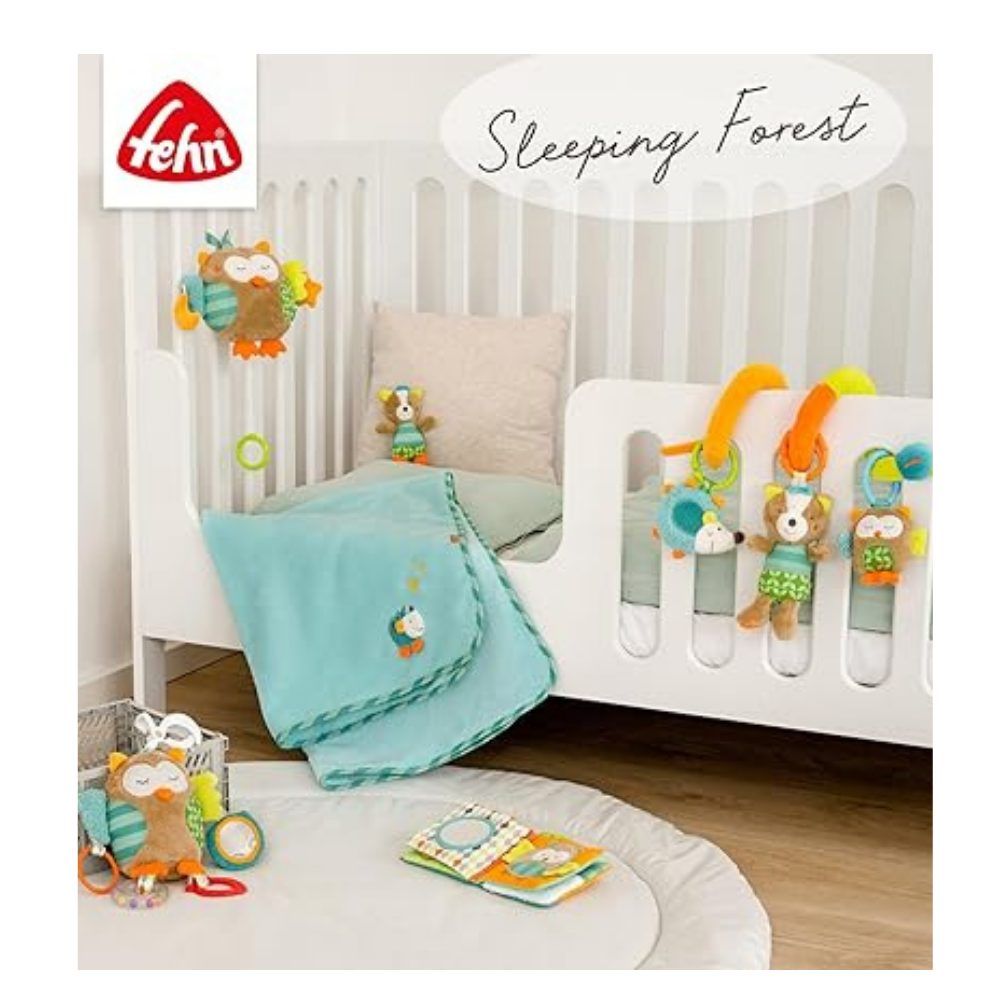 Baby-Spielzeug-Set mit Stoffbuch und Stofftieren. Marke: fehn. Auf einem weißen Kinderbett. Im Hintergrund: Spielzeug und Dekoration.