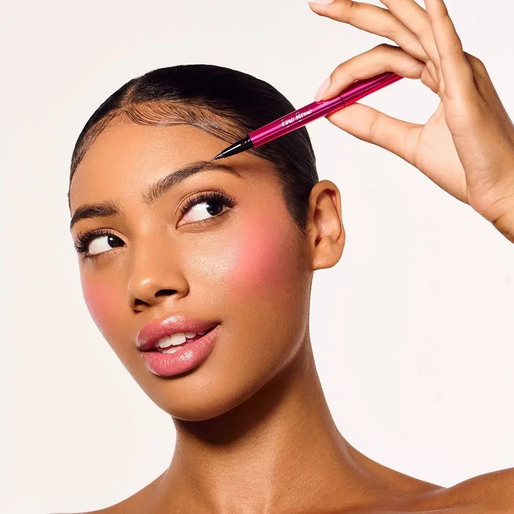 Frau mit pinkfarbenem Stift, der die Augenbraue berührt. Stift mit Schriftzug: BODYOGRAPHY Epic Brow.