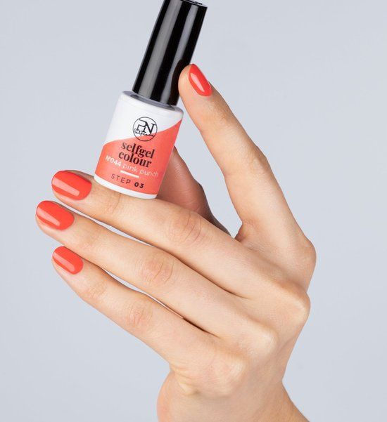 Hand mit lackierten Nägeln und Nagellackflasche. Flasche mit Aufschrift "selfgel colour". Nagellackfarbe: Pink.