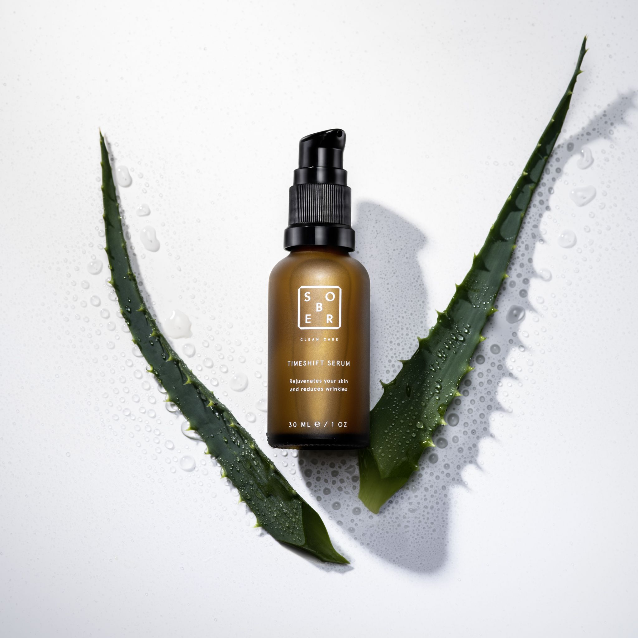 Braune Serumflasche mit schwarzem Pumpkopf, umgeben von Aloe Vera Blättern. Produktname und Text sichtbar.