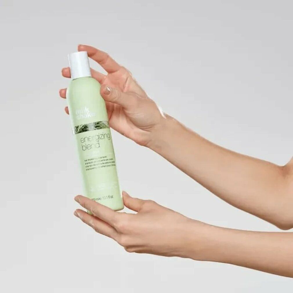 Hellgrüne Shampoo-Flasche mit weißem Deckel. Aufschrift: energizing blend shampoo. In Händen gehalten.