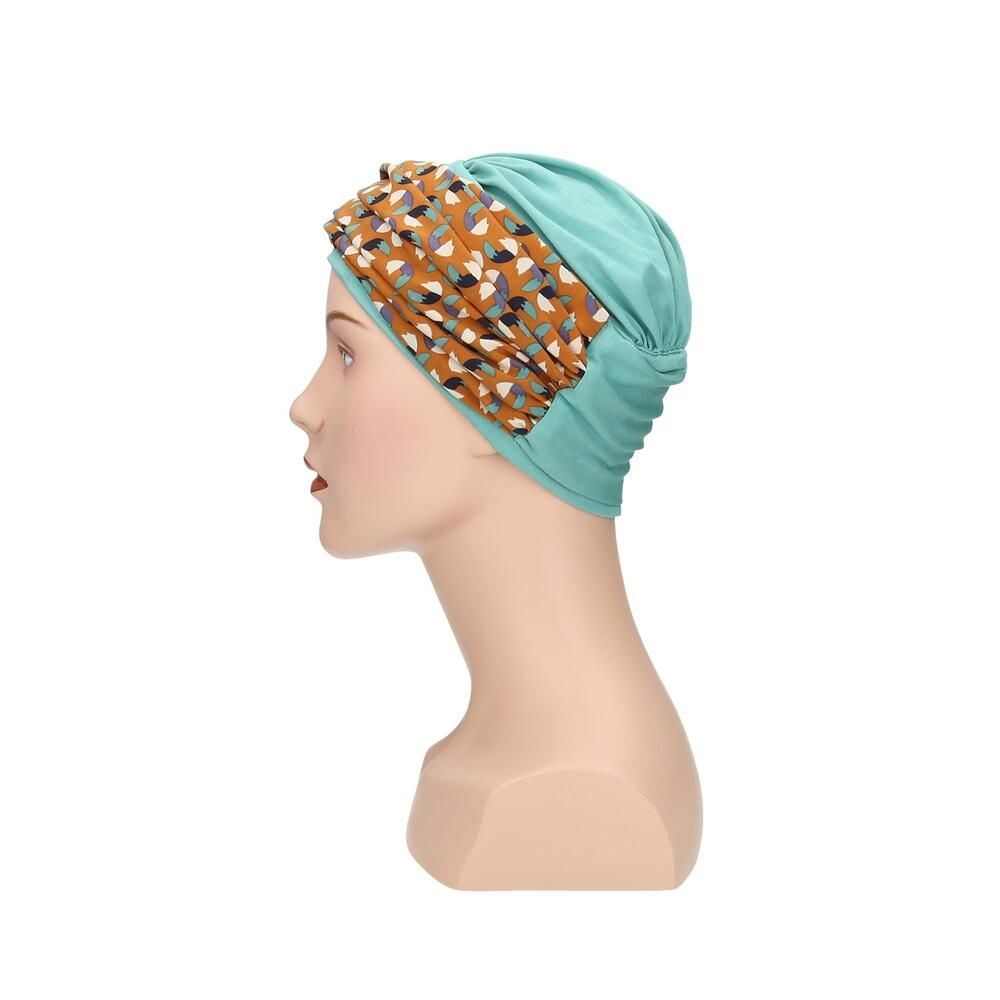 Türkisfarbener Turban mit gemustertem Stirnband auf einer Schaufensterpuppe. Das Stirnband hat ein Muster aus Braun-, Blau- und Beigetönen. Seitenansicht.