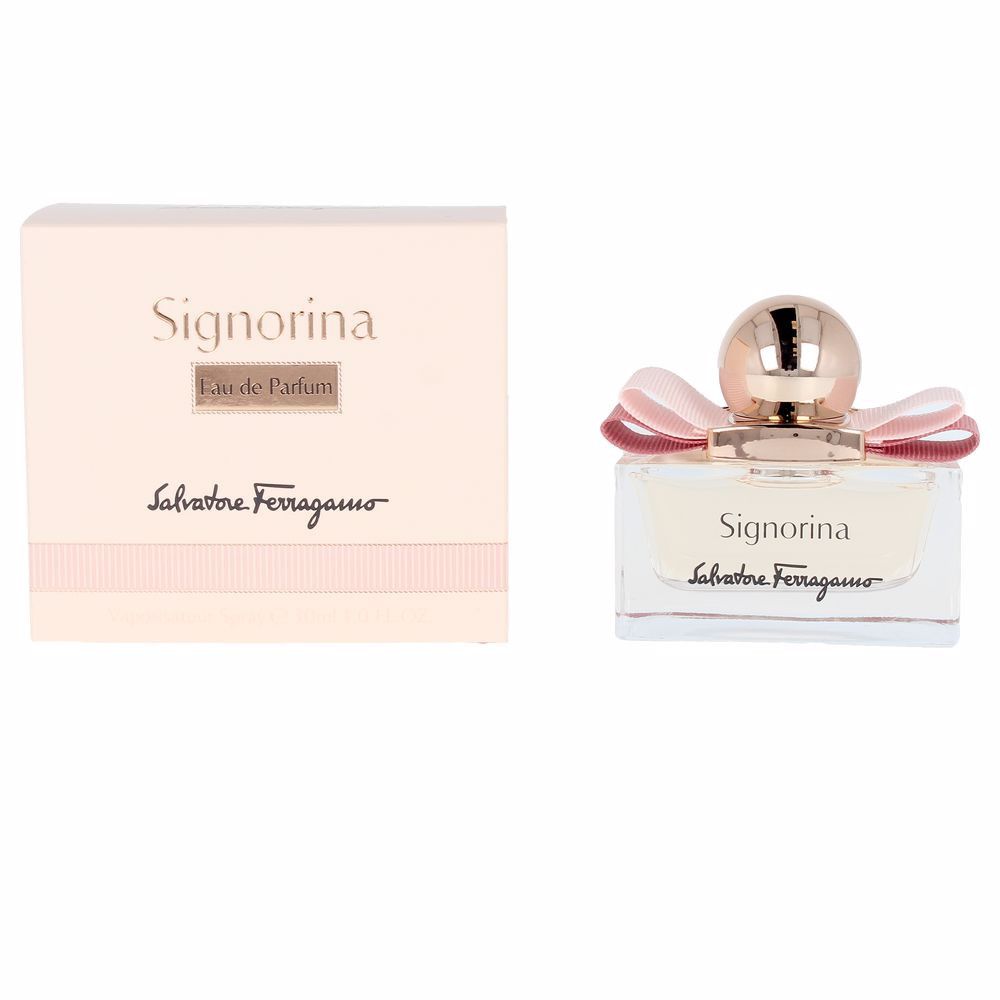 Signorina Eau de Parfum Spray. Rechteckiger Glasflakon mit rosa Flüssigkeit, rosa Schleife und goldfarbenem Verschluss. Verpackung daneben.