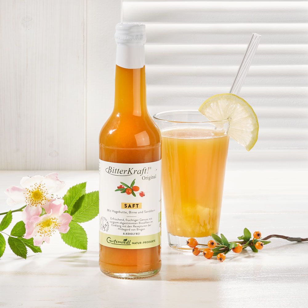 Flasche neben Glas mit Saft und Zitronenscheibe. Schriftzug "BitterKraft!". Bio-Siegel. Blüten und Beeren.